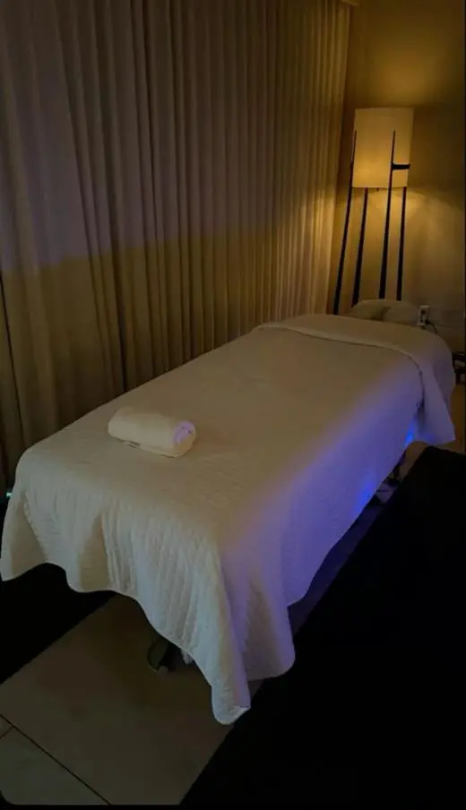 Treatment room with a massage table, soft lamp light, and curtains